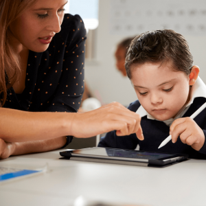 Female teacher with young student working on an iPad