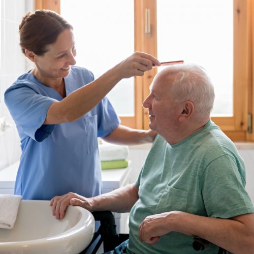 Home Caregiver with senior man in bathroom